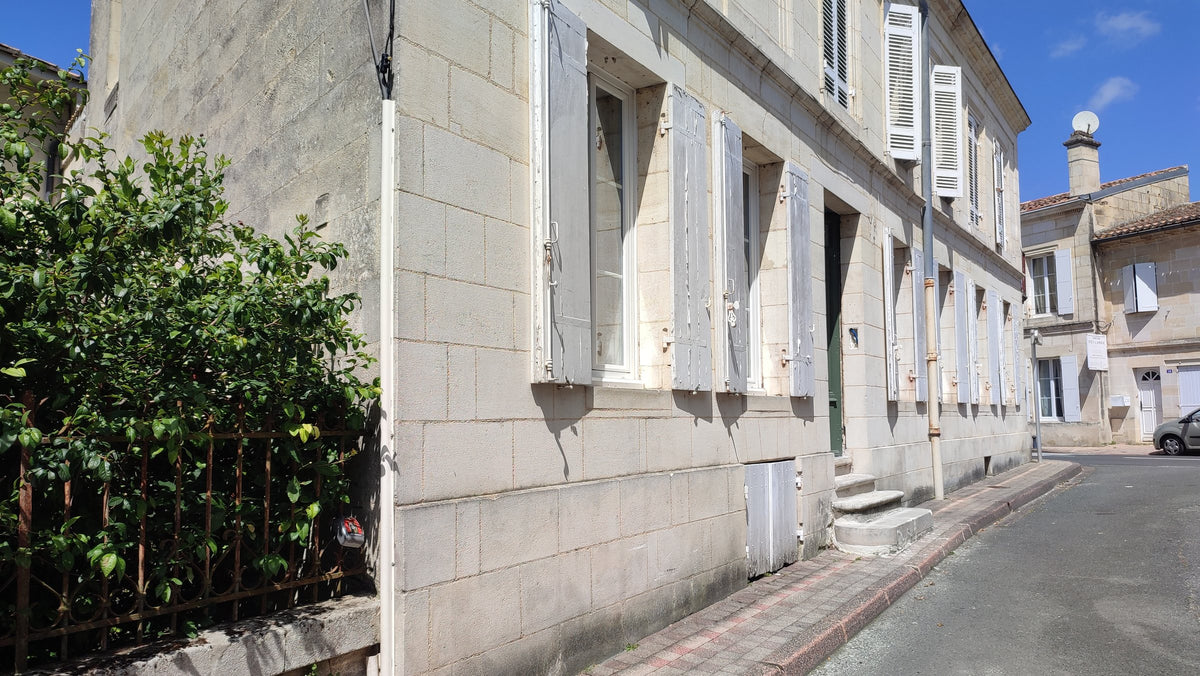 Façade en pierre du Pavillon, maison de maître aux volets blancs à Fronsac