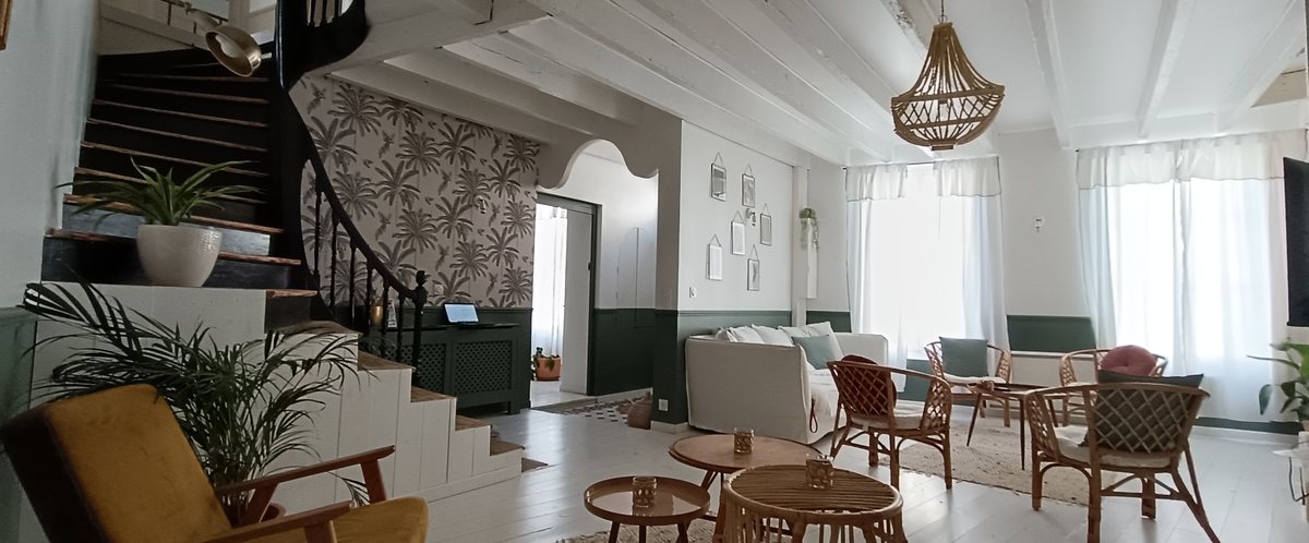 Salon du Pavillon : mobilier en rotin, grand escalier et suspension en rotin tressé