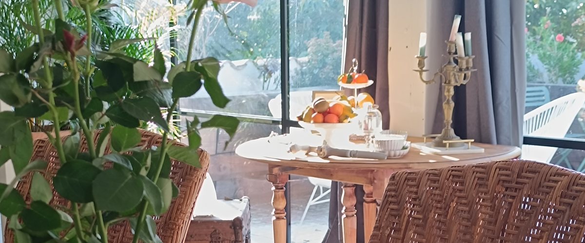 Table de petit déjeuner dressée sur la terrasse vitrée du Pavillon, fauteuils en rotin
