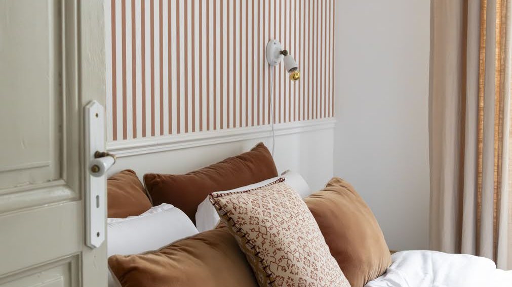 Chambre du Pavillon, lit blanc, coussins terracotta et porte patinée